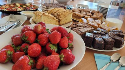 Gedeckter Tisch mit verschiedenem Kuchen, Gummibärchen und Erdbeeren, dazu Teller und Besteck