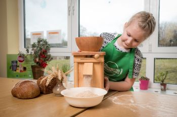 Ein Mödchen mahlt Mehr mit einer Mühle