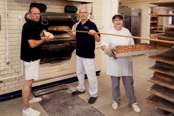 Drei Bäcker stehen in einer Backstube
