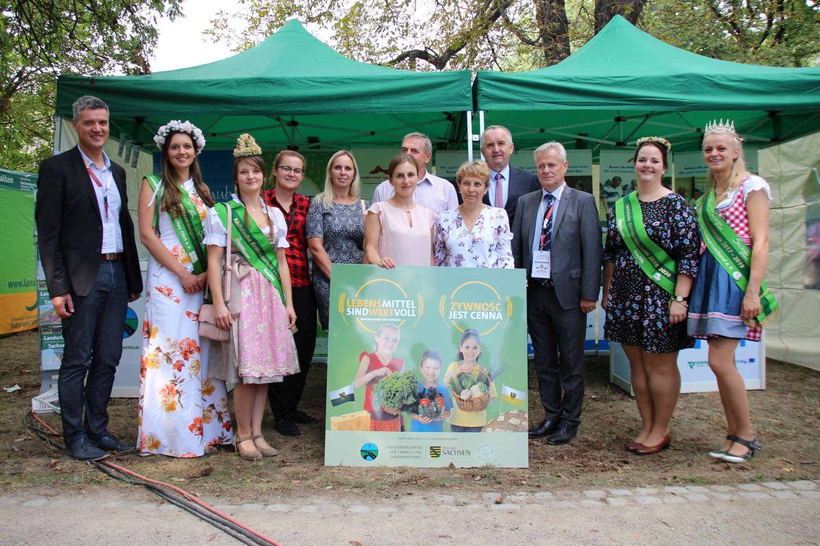 Zwölf Personen stehen vor zwei Stand-Zelten, vor ihnen ein Schild mit der Aufschrift: Lebensmittel sind wertvoll